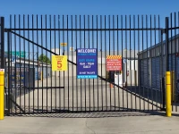 large black security gate with signs for storage hours and speed limit
