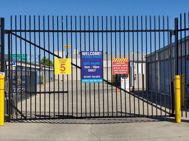 large black security gate with signs for storage hours and speed limit