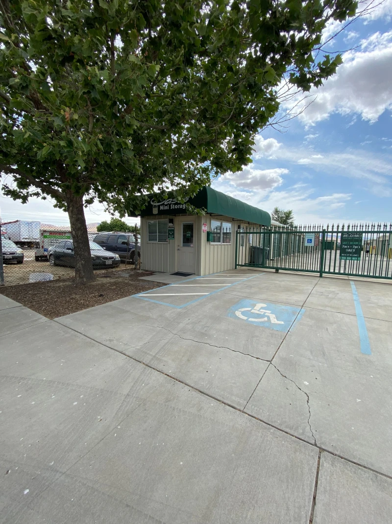 front view of a white and green storage facility under a large tree