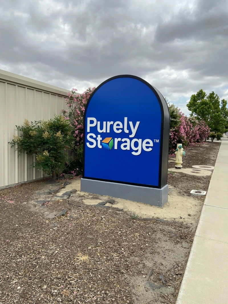 blue Purely Storage logo monument sign in garden bed of storage facility in Avenal