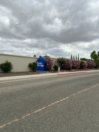 across street view of blue purely storage sign and green bushes with pink flowers