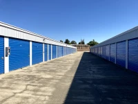 concrete drive aisle between two grey and silver storage buildings