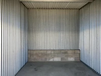 inside metal storage unit with cement floor and silver walls