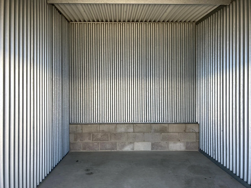 inside metal storage unit with cement floor and silver walls